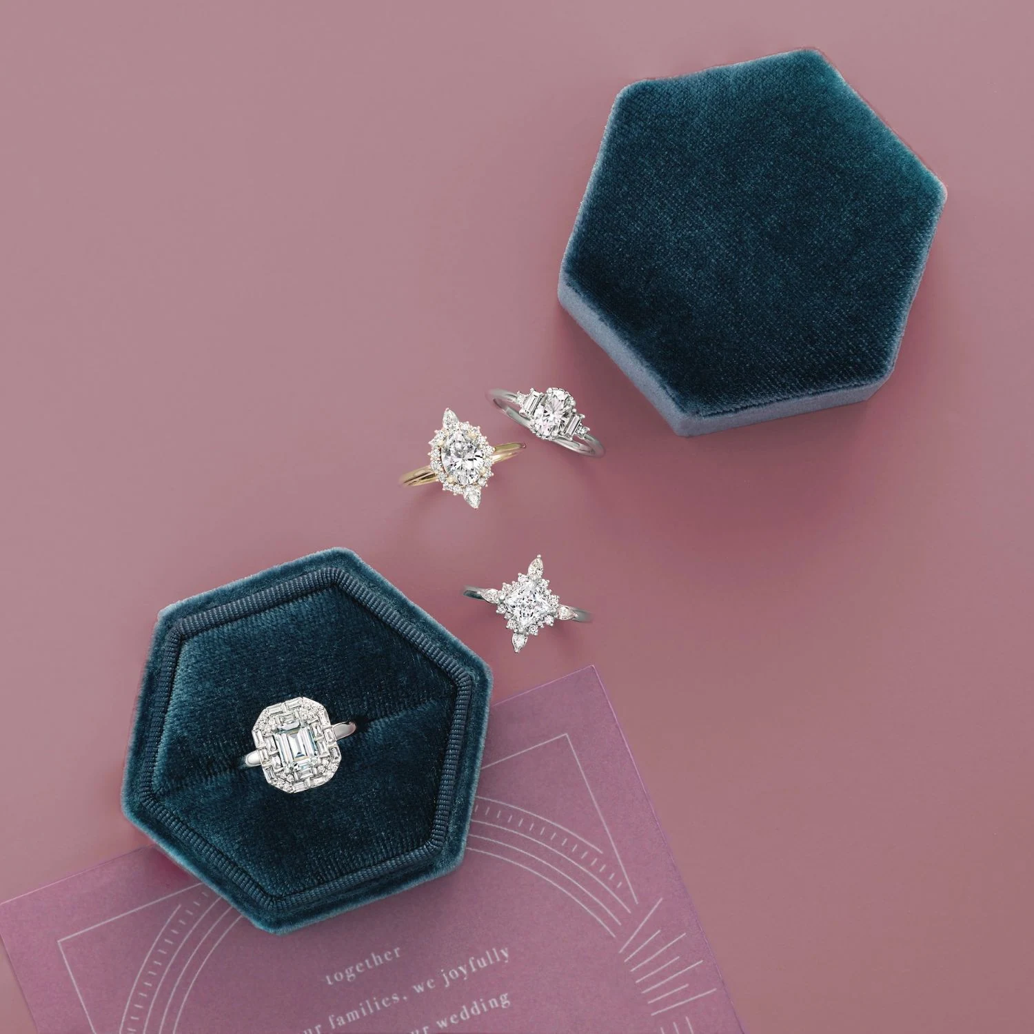 Emerald cut halo and unique diamond rings in velvet boxes on dusty rose background